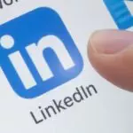 A finger about to tap the LinkedIn app icon on a touchscreen device, ready to explore LinkedIn jobs in Charlotte, NC.